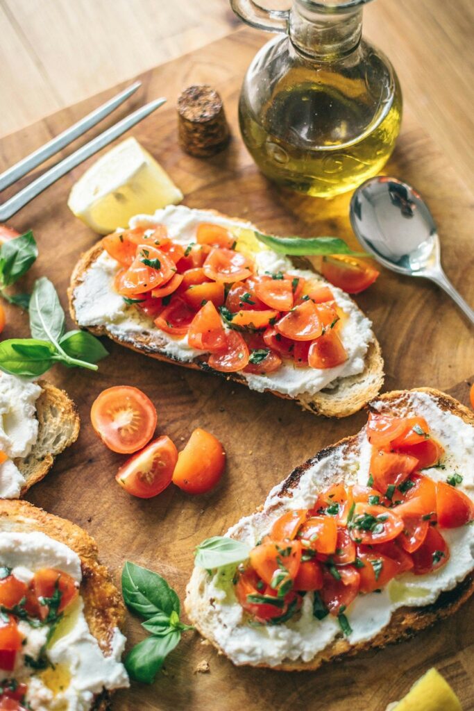 Menu Bruschetta with tomatoes and cream cheese on a wooden board