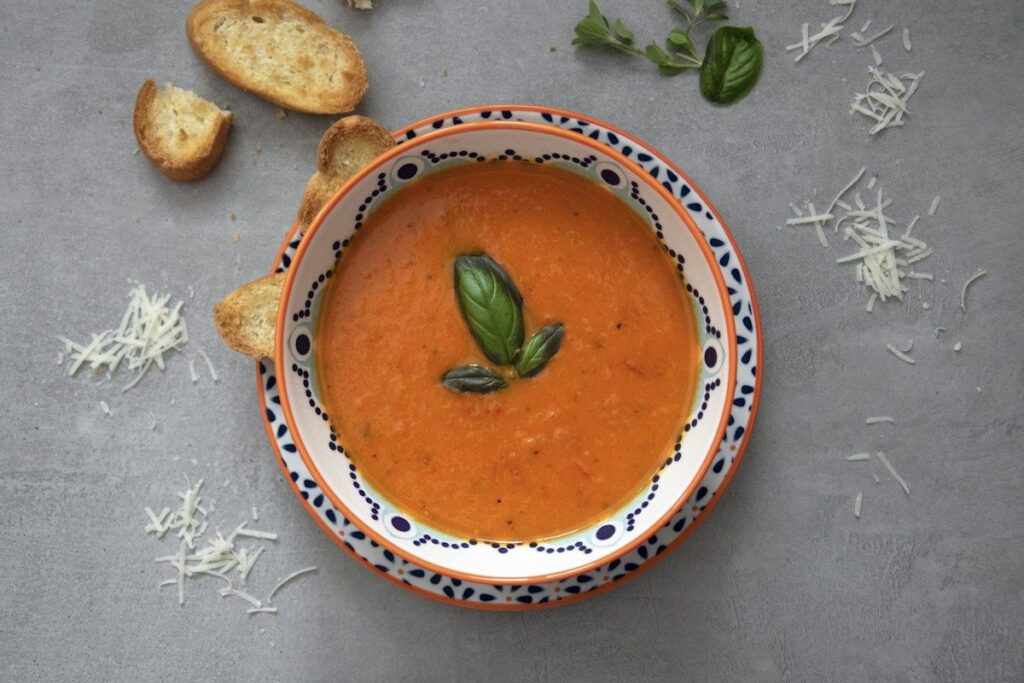 Menu Cream of tomato soup with basil in a colorfully painted bowl