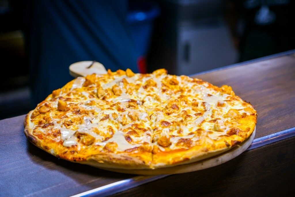 Menu Pizza with chicken and cheese on a wooden board
