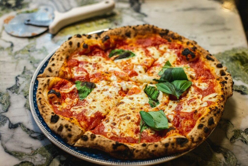 Menu Pizza Margherita from the stone oven with basil on a plate
