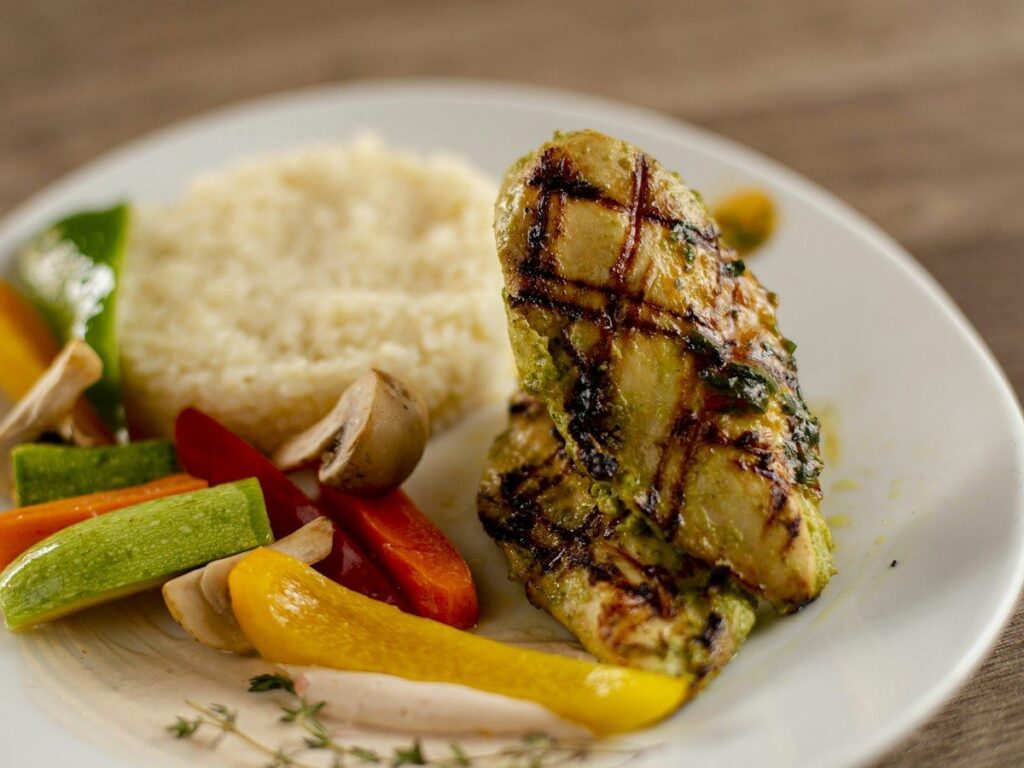 Menu Grilled chicken breast with rice and vegetables on a plate