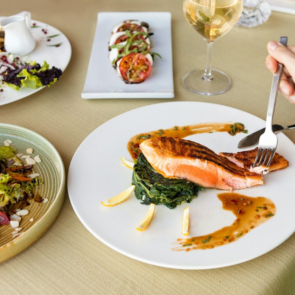 Menu Salmon fillet with spinach and sauce on a white plate