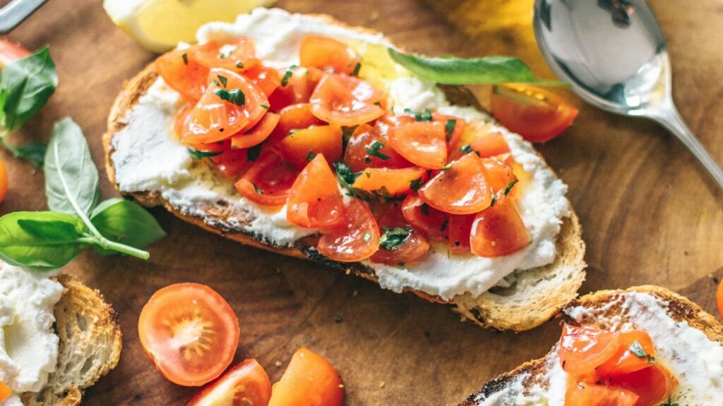 Menu Bruschetta with tomatoes, cream cheese and basil on a wooden board