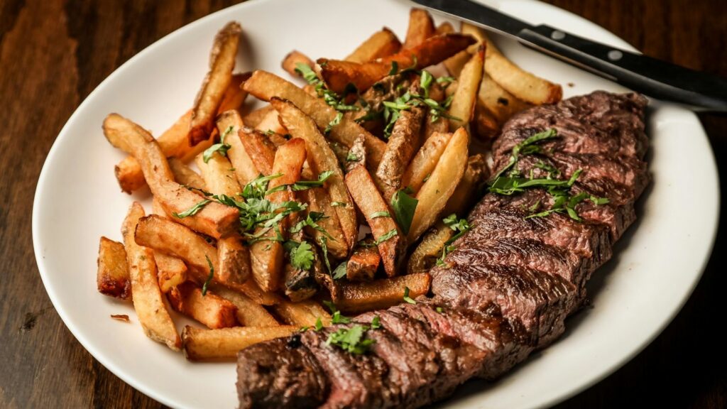 Gegrilltes Rinderfilet mit Pommes frites auf weißem Teller